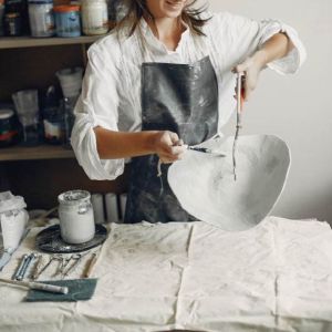 Frauen glasieren große Keramikteller mit Tauchglasur im Keramikstudio Zolta