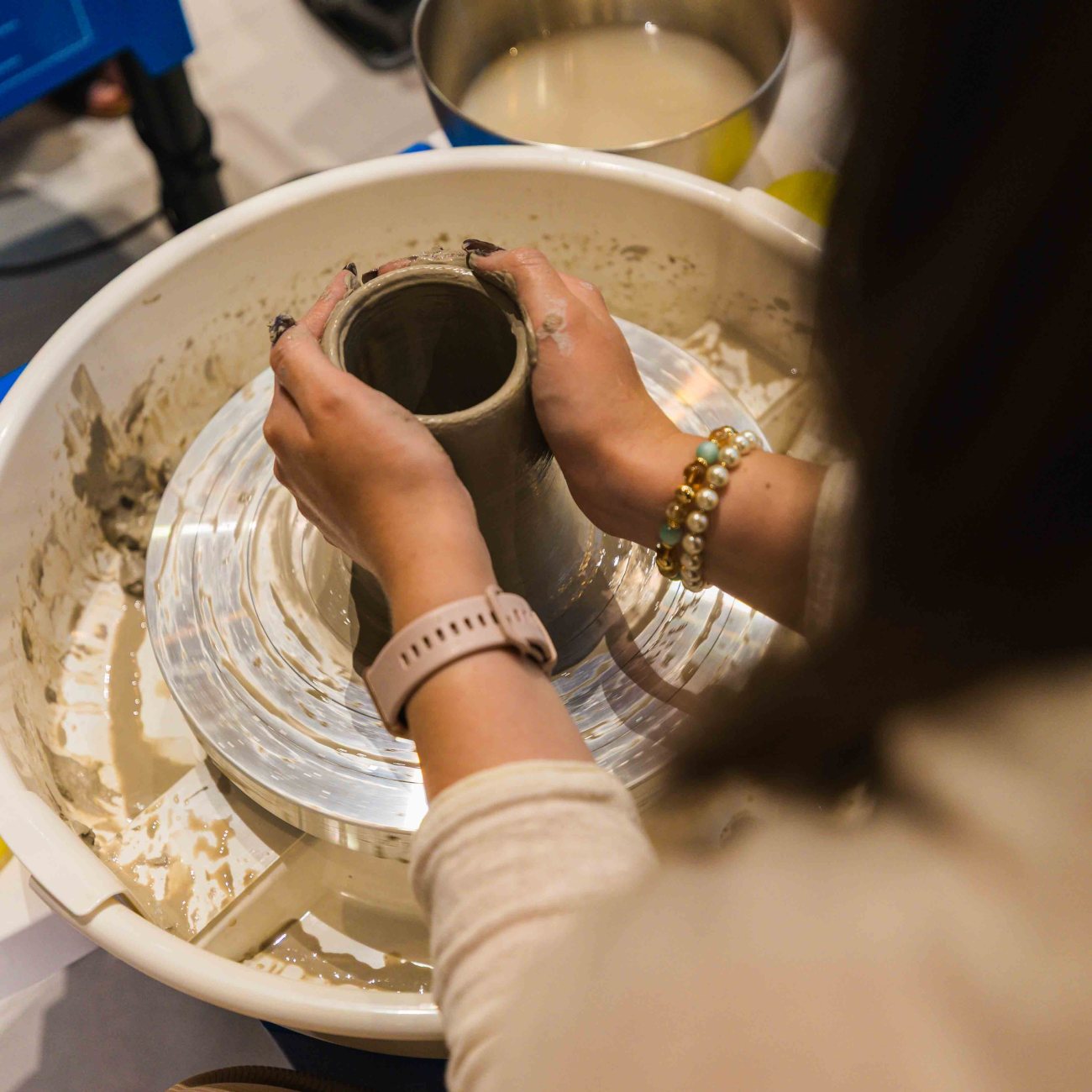 a close-up of a woman throwing clay on the pottery wheel, holding the piece in her hands during a pottery workshop at Zolta Ceramics Studio Vienna