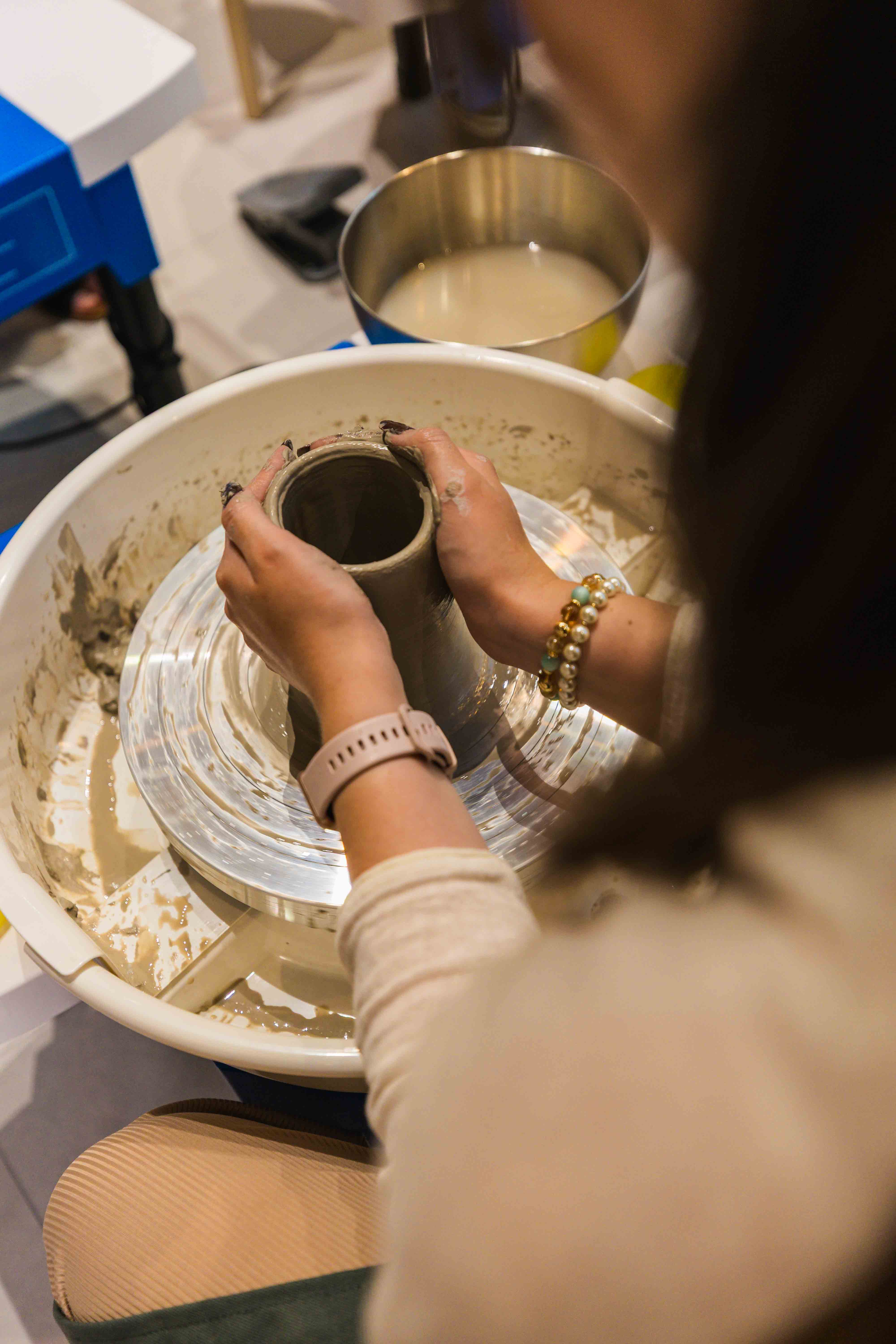 a close-up of a woman throwing clay on the pottery wheel, holding the piece in her hands during a pottery workshop at Zolta Ceramics Studio Vienna
