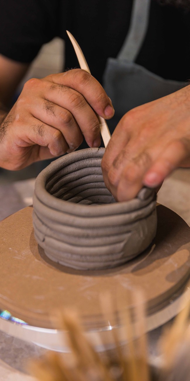 a close-up to a man making pottery using coils at Zolta Ceramics Studio