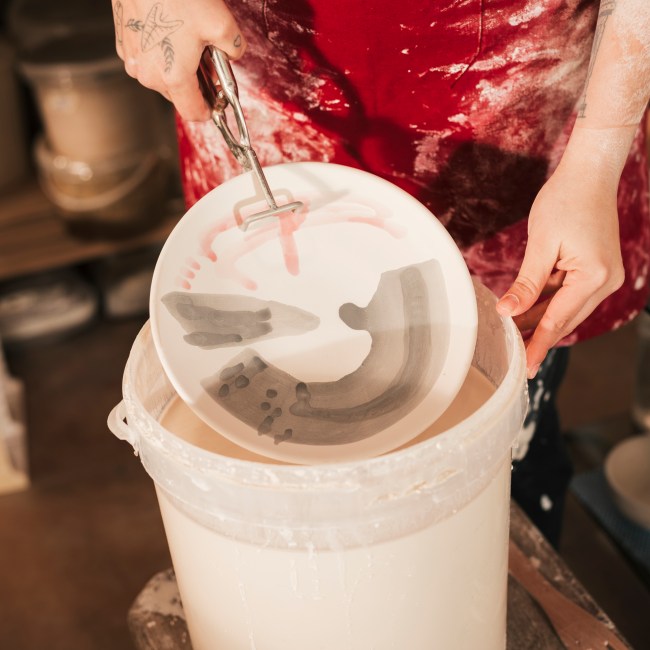 female-craftswoman-painting-ceramic-dish-with-paint-workshop ceramic-glazing-workshop