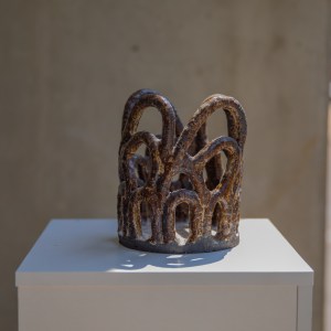 Handbuilt ceramic vessel by artist Sirin AlMasri, featuring an open lattice structure of interwoven arches in dark, sand-textured stoneware with a transparent glaze finish. Inspired by Middle Eastern architectural forms.