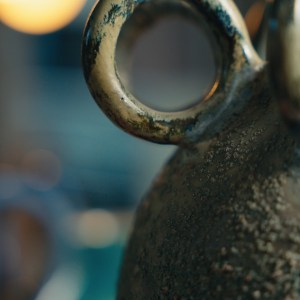 Handcrafted ceramic art piece titled “The Summoning” by Sirin AlMasri in Zolta Studio, featuring five sculptural loop handles and a textured volcanic glaze in deep green, blue, and charcoal tones. Modern interpretation of ritual pottery with oxidized copper surface effects.