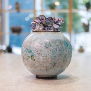 Stoneware sculpture Flower Bomb by Sirin AlMasri at Zolta Ceramics Studio Vienna — round vessel with textured turquoise-beige body and red petal-like glazed crown.